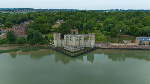 Aerial view of Upnor Castle on the banks of the River Medway, surrounded by lush green trees and historic buildings under an overcast sky in Upper Upnor, England, United Kingdom.