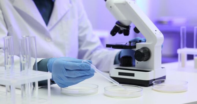Laboratory testing. Scientist examining sample of milk under microscope at white table indoors, closeup