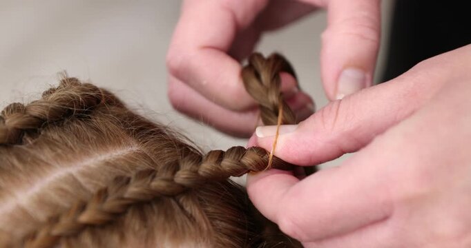 Hair braiding. Hairdresser working with teenage girl indoors, closeup