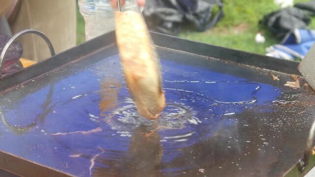 a person's hands cooking square shaped egg martabak and burger patty meat on a hot flat pan