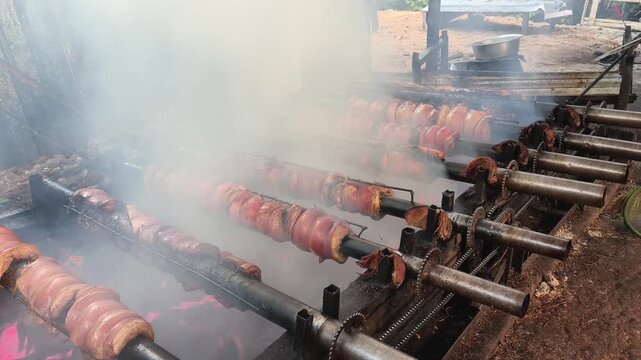 Balinese Samsam Guling Pork Belly Roasting on Rotisserie Spit over Charcoal