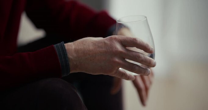 Hand holding an empty clear glass in soft indoor light