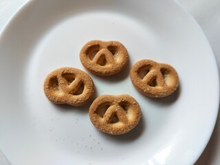 Naklejka premium Butter cookies neatly arranged on a plain white plate, showcasing their golden color, crisp texture, and delicious homemade appeal. Perfect for bakery, dessert, snack, and food-themed content.