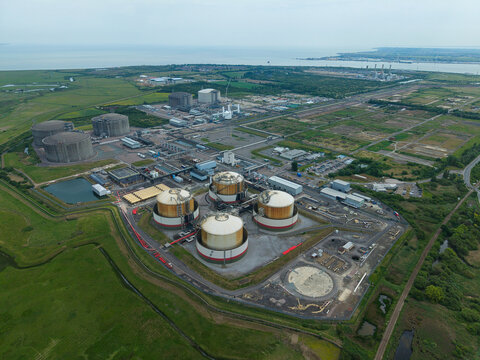 Aerial view of the Grain LNG terminal featuring large storage tanks and industrial infrastructure surrounded by green fields in Wallend, England, United Kingdom.