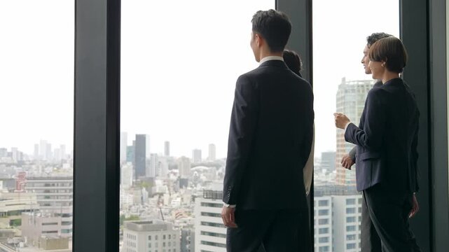 オフィスから外を眺めるビジネスパーソンのグループ