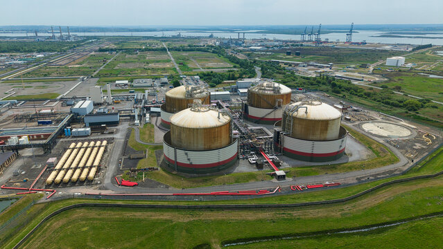 Aerial view of the Grain LNG terminal featuring large storage tanks and industrial infrastructure under a clear sky in Wallend, England, United Kingdom.