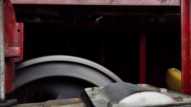 Large industrial engine flywheel spinning rapidly in slow motion macro close up