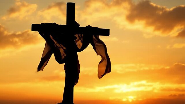 Silhouette of a cross draped with cloth against a dramatic sunset