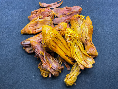 pile of dried Rampatri (Wild Mace) pieces isolated on a clean black background. The image showcases the intricate, reticulated, and lacy texture of these orange-brown whole spices. 