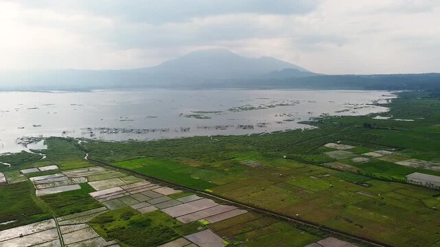 Aerial panorama of Rawa Pening Lake and agricultural landscape with mountain backdrop in Central Java, Indonesia
