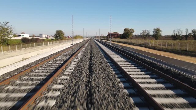 Aerial view of railway tracks stretching into the distance under a clear blue sky in Desenzano del Garda, Lombardy, Italy.