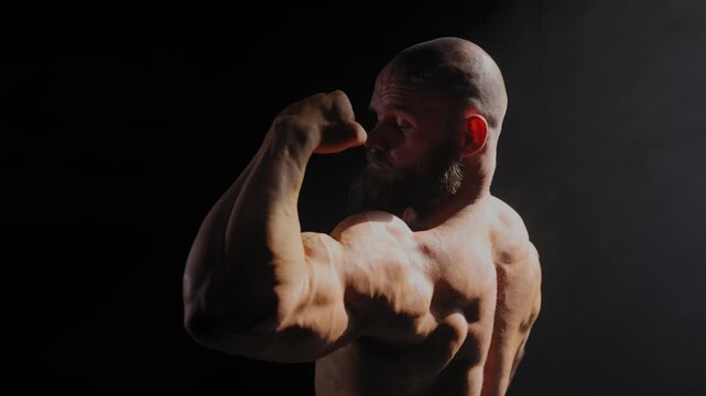 A male bodybuilder poses in shorts, showing off his back muscles.
