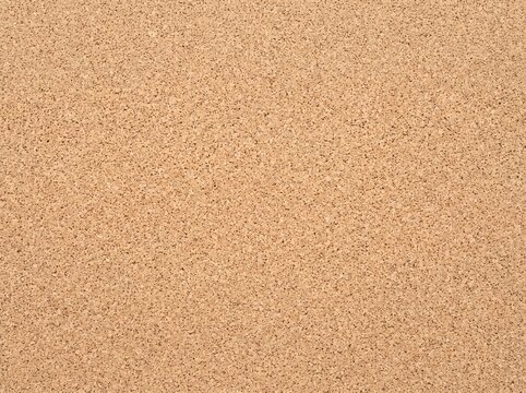 Close-up view of a light brown textured cork board surface, ideal for backgrounds and design elements.