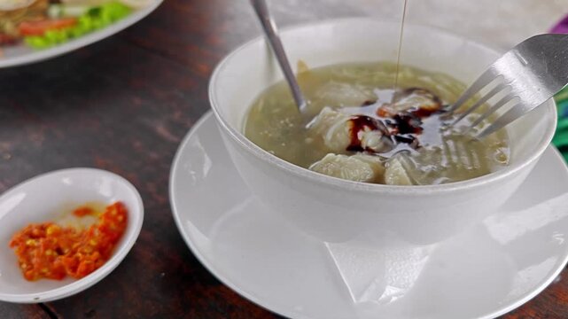 Adding Sweet Soy Sauce to Indonesian Tekwan Fish Ball Soup