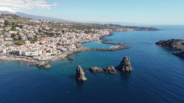 Aerial view of the Islands of the Cyclops rock formations in the blue Mediterranean sea near the harbor of Aci Castello, Catania, Italy.