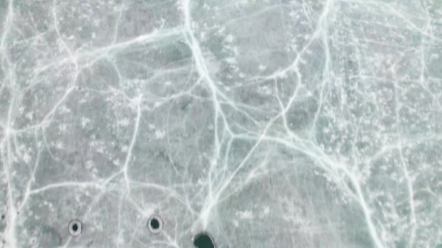 Drone view of half frozen lake with ice on water, close up view of blue ice crack and bubbles in earl spring day, top view ice floating on lake, 4k real time footage travel concept.