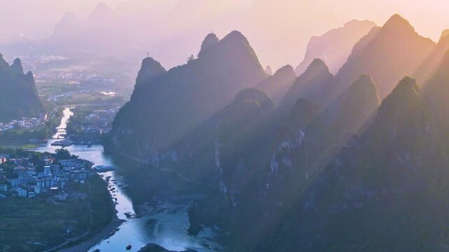 Forward aerial drone view of Guilin Li River karst mountains at sunrise, golden sun rays across limestone peaks, drifting fishing boat on winding river, iconic Guilin natural landscape, Guangxi China