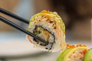 Chopsticks picking up avocado shrimp sushi roll © Dong