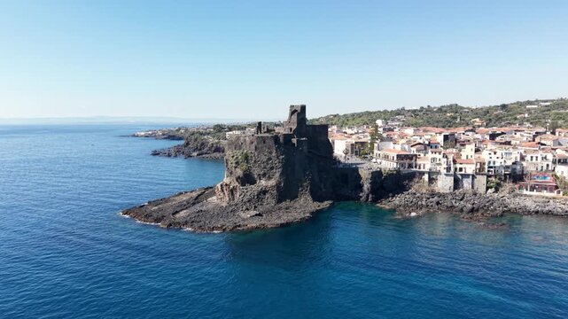 Aerial view of the ancient Norman Castle on a rocky promontory overlooking the blue Mediterranean Sea and the coastline of Sicily, Italy.