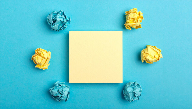 Blank yellow sticky note with crumpled paper balls brainstorming concept