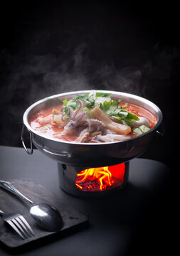 Thai pink noodle soup Yentafo seafood hot pot with steam on dark background.