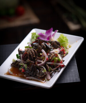 Thai spicy fermented crab salad with shallot and chili on white plate.