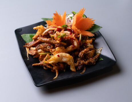 Thai spicy crispy salad Yum Sam Krob with cashew nuts on black plate.