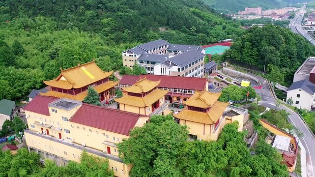 Aerial view of a secluded traditional Chinese temple complex with yellow walls and red tiled roofs, surrounded by forested mountain slopes in China. Emphasizes the contemplative setting of classic Chi