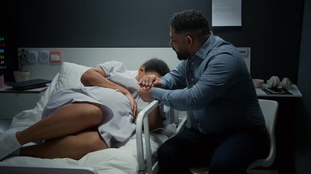 pregnant woman experiencing labor pain in hospital bed while husband holds her hand. Clip is ideal for maternity healthcare services,family planning,and medical insurance advertising