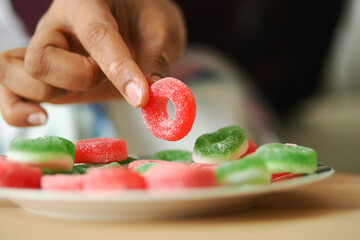 Obraz premium Person picks a gummy candy from a plate on a table