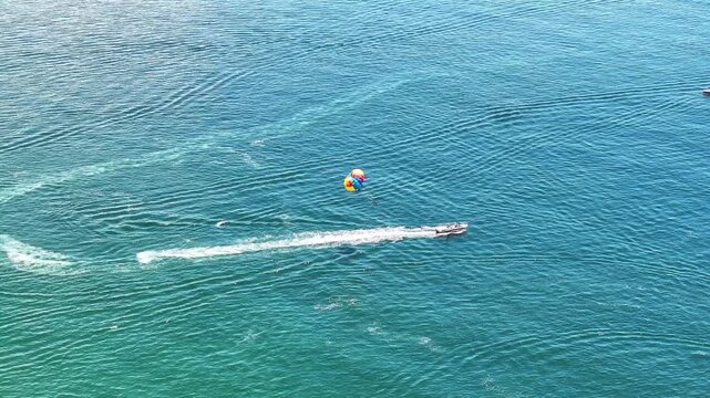 Aerial view of speedboat towing parasail over blue ocean