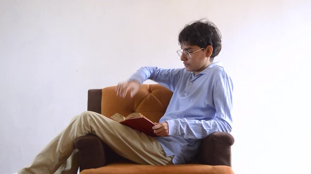 young man sitting on a sofa and reading a book