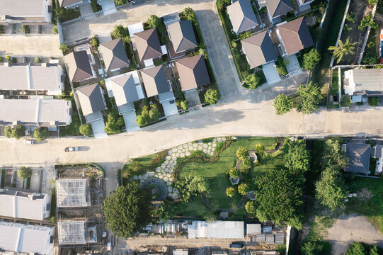 Aerial view of suburban housing development featuring residential homes, neighborhood streets, green spaces, landscaped properties, and urban planning layout. Highlights real estate, community.