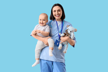 Young female pediatrician with toy and cute little baby on blue background © Pixel-Shot