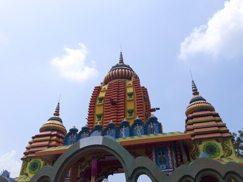 Sri Hathi Kheda Thakur Hindu temple architecture with intricate carvings and vibrant colors under blue sky with clouds.