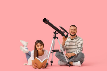 Obraz premium Young couple with telescope and book on pink background