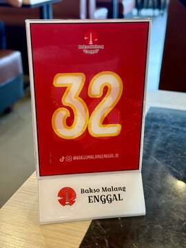 Jakarta, Indonesia - May 15, 2026: A close-up shot of a wooden dining table displaying table number 32 marker at the Bakso Malang Enggal restaurant in Cibubur