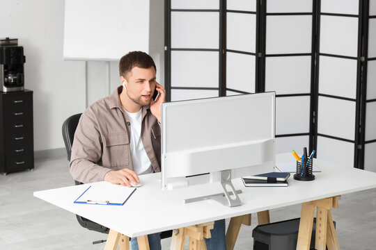 Portrait of male programmer talking by phone while working in office