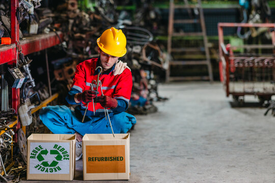 Male technician inspecting used auto parts for refurbishing and recycling in scrapyard