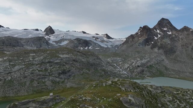 Aerial view of the Rutor Glacier and surrounding rocky peaks with alpine lakes and a small stone chapel Aosta Valley, Italy.