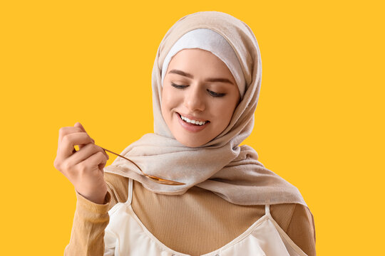 Muslim woman with spoon on yellow background, closeup