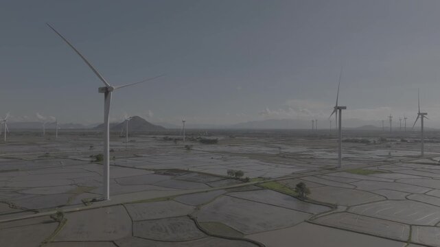 Aerial drone footage of Dam Nai Wind Farm in Khanh Hoa, Vietnam, featuring rows of wind turbines across coastal wetlands, showcasing renewable energy, sustainable power and scenic landscape.