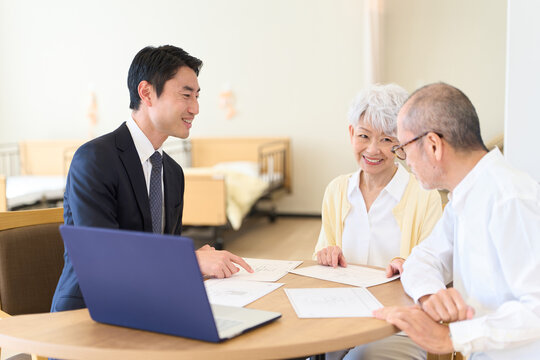 シニアに営業をするアジア人ビジネスマン