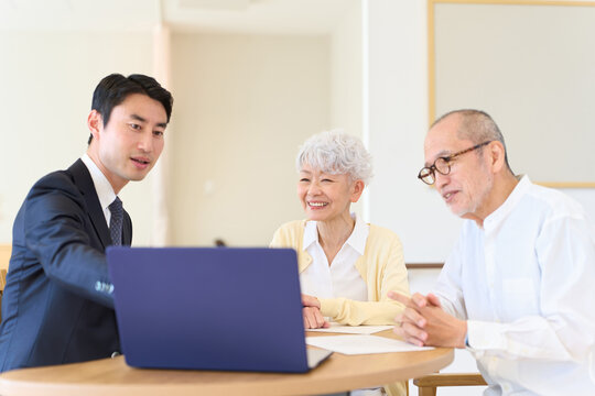 シニアに営業をするアジア人ビジネスマン