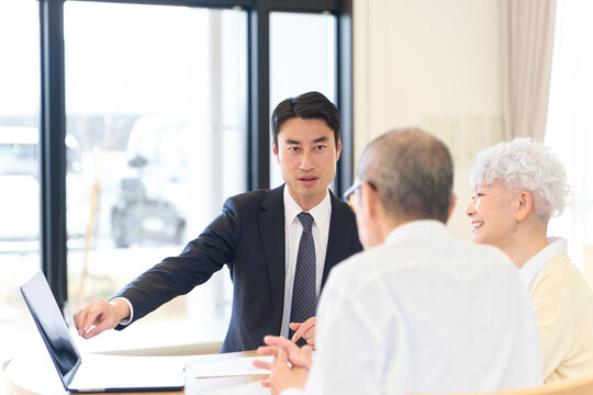 シニアに営業をするアジア人ビジネスマン