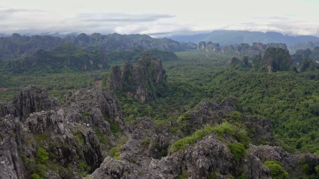 Drone flying over a landscape of limestone cliffs and tropical forest in a national park in Laos PDR.