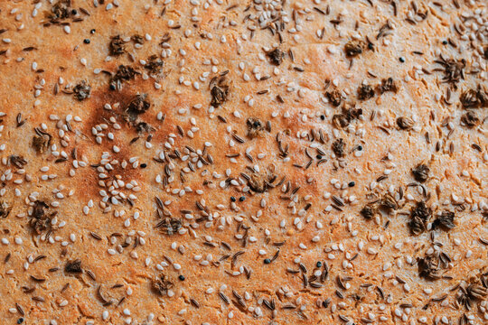 Close-up of a seed-encrusted bread surface showing sesame and cumin seeds.