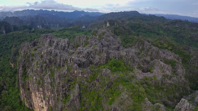 Drone flying over a landscape of limestone cliffs and tropical forest in a national park in Laos PDR.