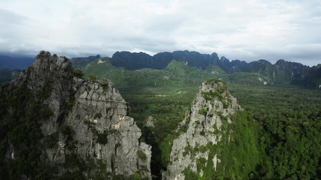 Drone flying over a landscape of limestone cliffs and tropical forest in a national park in Laos PDR.
