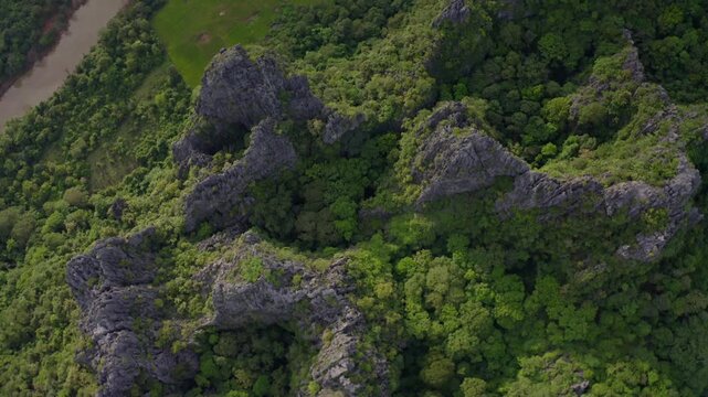 Drone flying over a landscape of limestone cliffs and tropical forest in a national park in Laos PDR.